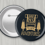 Black 4" round pin back button with gold 'Say Yes to New Adventures' logo